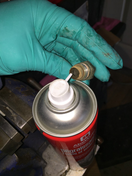 On pulvérise avec le nettoyant freins dans les 2 orifices.<br />(On peut également utiliser un nettoyant pour carburateur).